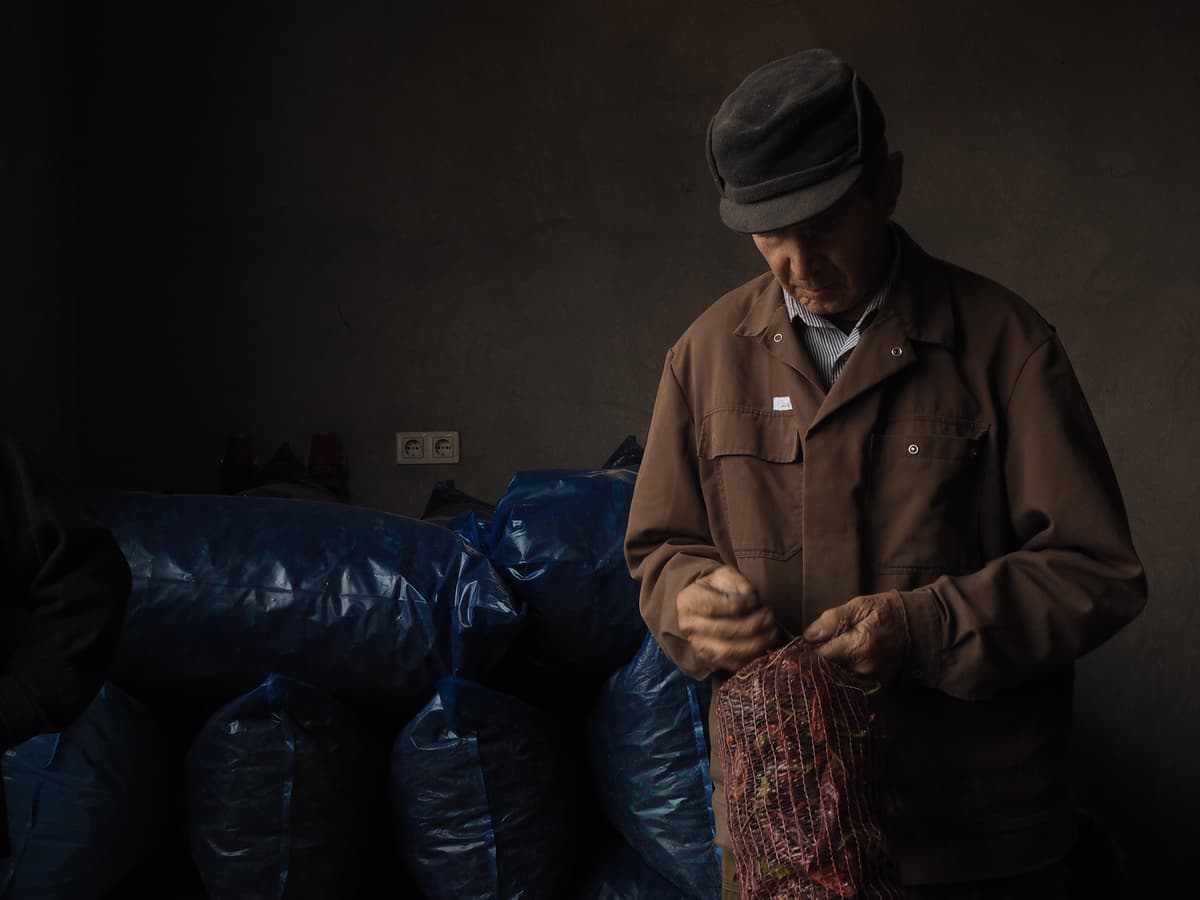 Worker tying a mesh bag of dried peppers.