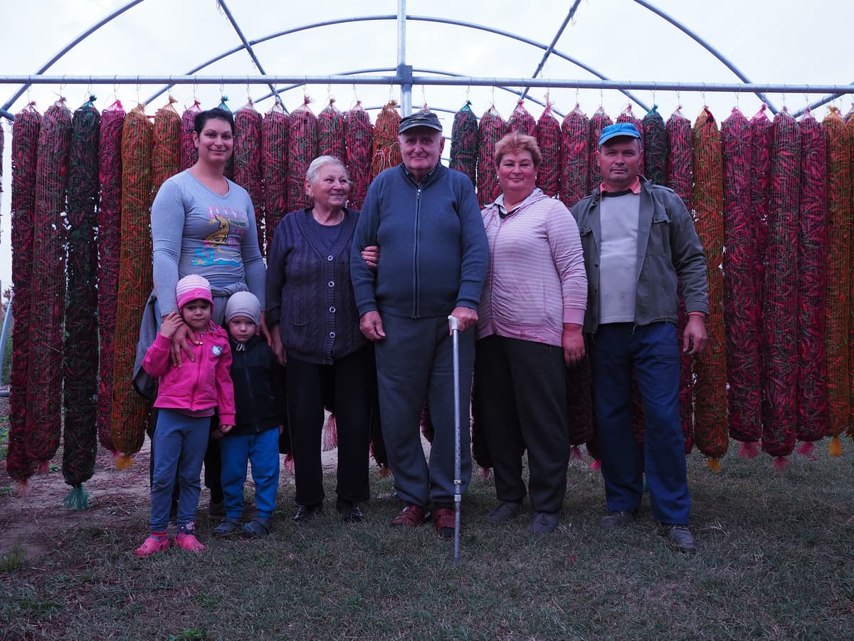 Family standing in front of drying pepper racks.